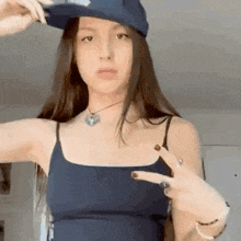 a young woman wearing a hat and a blue tank top is giving the middle finger .