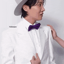 a man in a white suit with a purple bow tie is being touched