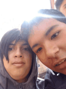 two boys are posing for a picture and one has a hood on