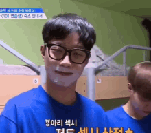 a young man wearing glasses and a blue shirt with foreign writing on it