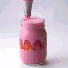a mason jar filled with pink liquid and strawberries is being decorated