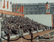 a crowd of people are gathered in front of a sign that says volksfreundschaft und spezialismus