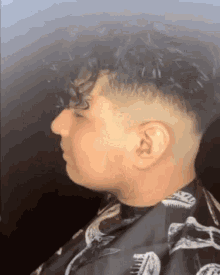 a man with curly hair is getting his hair cut by a barber in a barber shop .