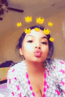 a woman with yellow crowns on her face is blowing a kiss .