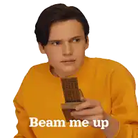 a young man in a yellow sweater holds a piece of wood and says beam me up