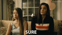 two women are sitting on a couch and the word sure is on the screen