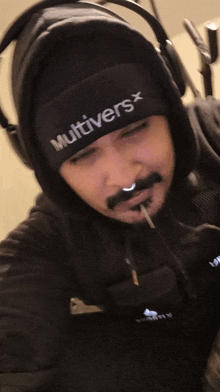 a man wearing headphones and a beanie with the word muffled on it is smoking a cigarette
