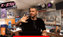 a man sitting at a desk in front of a sign for k-eth 101.1