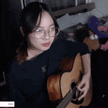 a girl with glasses is playing an acoustic guitar with a $ 500 price tag