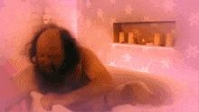 a man is laying in a bathtub with pink stars on the wall behind him