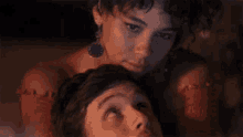 a man and a woman are sitting next to each other and the woman is looking at the man 's face .