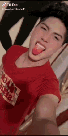 a young man in a red shirt is sticking his tongue out ..