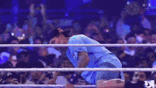 a man in a blue shirt is in a wrestling ring surrounded by fans