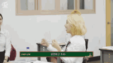 a girl with blonde hair is sitting at a desk in front of a chalkboard with the name dahyun on it