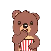 a teddy bear is holding a striped bucket of popcorn in its paws
