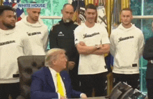 a man in a suit and tie is sitting at a desk in front of a group of men in juventus shirts .