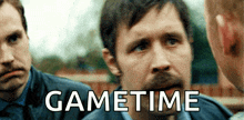a man with a beard is talking to two other men with the words gametime written on the bottom