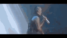 a man is singing into a microphone on a stage in the dark .