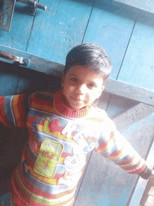 a young boy wearing a colorful sweater with the letters a and g on it