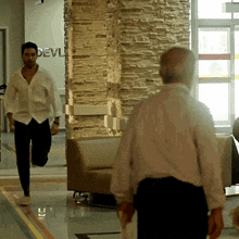 a man in a white shirt is running in front of a wall that says devil