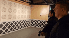 a group of men are standing in front of a wall with circles on it