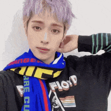 a man with purple hair is wearing a scarf around his neck and a floyd shirt