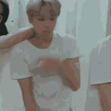 a man in a white t-shirt is standing next to another man in a white shirt .