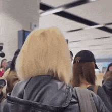 a woman with blonde hair is standing in a crowd of people .