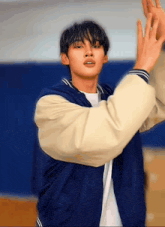 a young man in a blue and white baseball jacket is dancing .