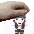 a hand is holding a stuffed doll on top of a white surface .