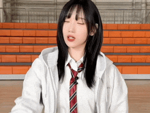 a girl wearing a tie and a white jacket stands in front of orange bleachers