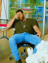 a man with a beard is sitting in a chair with his legs crossed