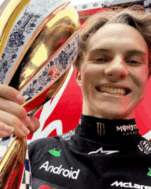 a young man holding a trophy that says android on his shirt