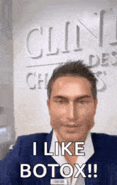 a man in a suit says " i like botox " in front of a sign