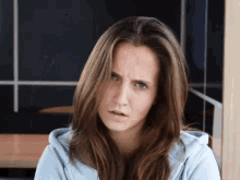 a woman in a blue hoodie is making a serious face