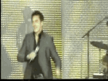 a man in a suit is singing into a microphone and dancing on a stage .