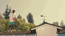 a man standing on a roof holding a skateboard