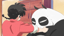 a girl in a red jacket is standing next to a panda bear