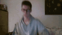 a blurry picture of a man wearing glasses and a grey shirt