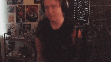 a man wearing headphones is holding a microphone in front of a wall with posters on it