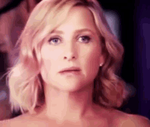 a woman with blonde hair and blue eyes is making a funny face .