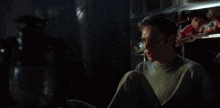 a man is sitting in a dark room with a shocked look on his face
