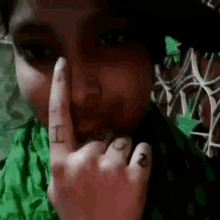 a woman with a tattoo on her finger is holding her finger to her mouth .