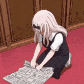 a girl is kneeling down on the floor reading a newspaper
