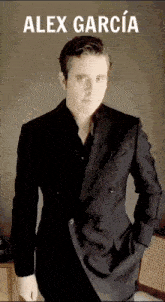 a man in a suit is standing with his hands in his pockets and the name alex garcia is above him