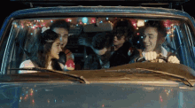 a group of people are sitting in a car with christmas lights on