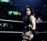 a woman in a black outfit is standing in a wrestling ring with a w logo in the background .