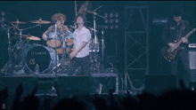 a man is singing into a microphone in front of a drum set that says osakae
