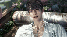 a man wearing a white shirt and a necklace is laying on a couch .