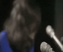 a man with long hair is singing into a microphone while another man watches .